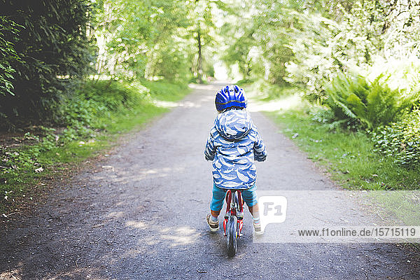 Rückenansicht des Kleinkindes Mädchen mit blauem Fahrradhelm auf Drehgestellrad