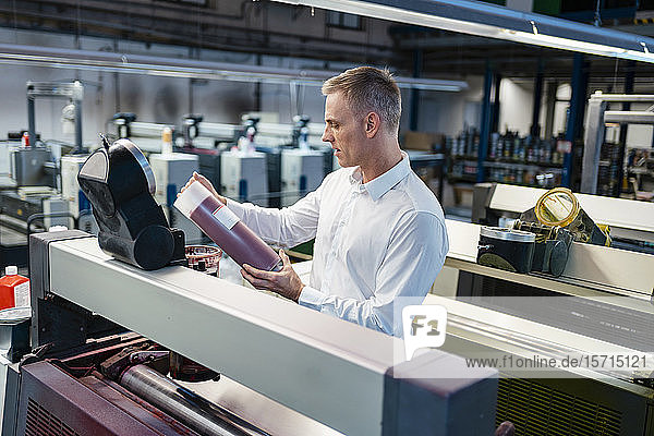 Man in white shirt in a factory examining product