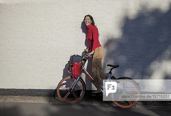 Carefree young woman riding a rental bike