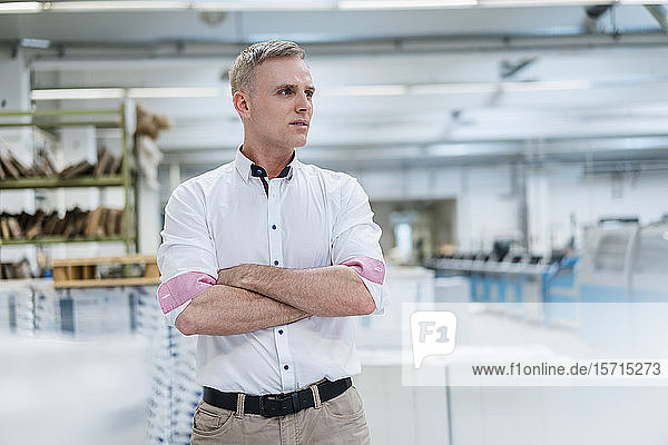 Man in white shirt in a factory looking around