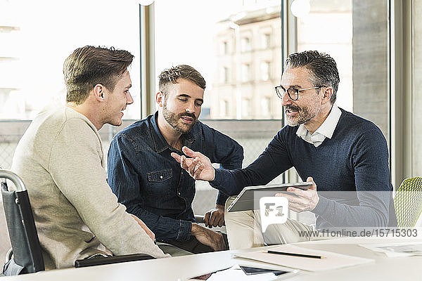 Drei Geschäftsleute treffen sich im Büro und teilen sich ein Tablett