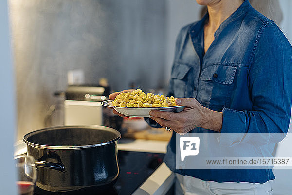 Nahaufnahme einer Frau  die zu Hause in der Küche einen Teller mit Tortellini hält