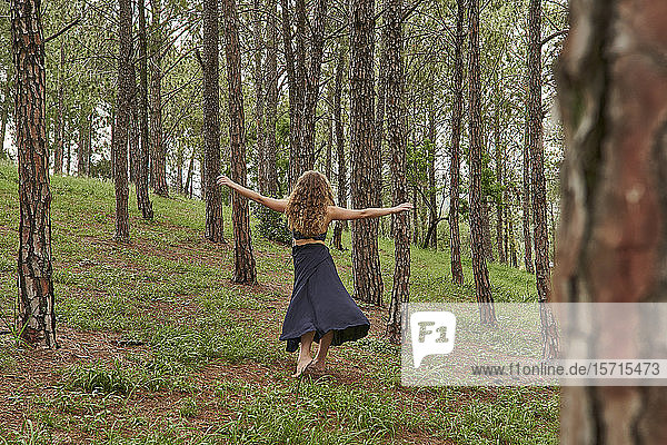 Rückenansicht einer barfüssigen jungen Frau  die im Wald tanzt
