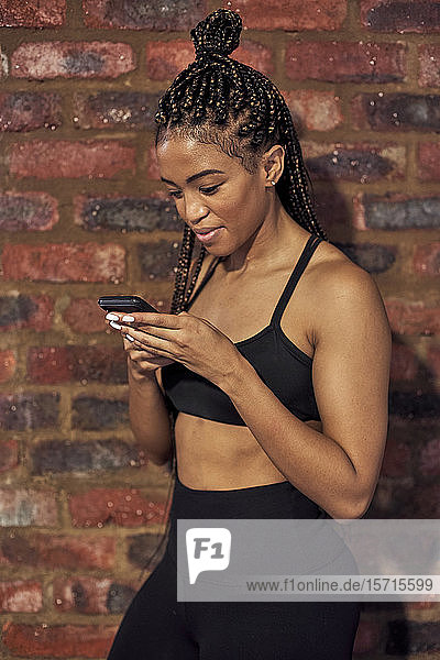 Weibliche Sportlerin benutzt Smartphone nach dem Training