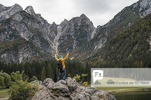 Hiker on viewpoint with raised arms at Laghi di Fusine Friuli Venezia Giulia Italy