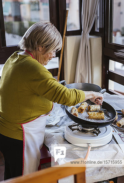 Ältere Frau bereitet spanisches Weihnachtsgebäck Pestinos