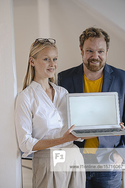 Porträt eines selbstbewussten Geschäftsmannes und einer selbstbewussten Geschäftsfrau im Büro bei der Präsentation eines Laptops