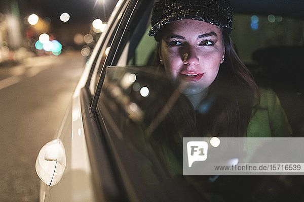 Frau  die nachts auf dem Rücksitz eines Autos in der Stadt sitzt