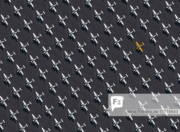 Luftbild eines einzelnen orangefarbenen Flugzeugs,  umgeben von ausschließlich weißen Flugzeugen