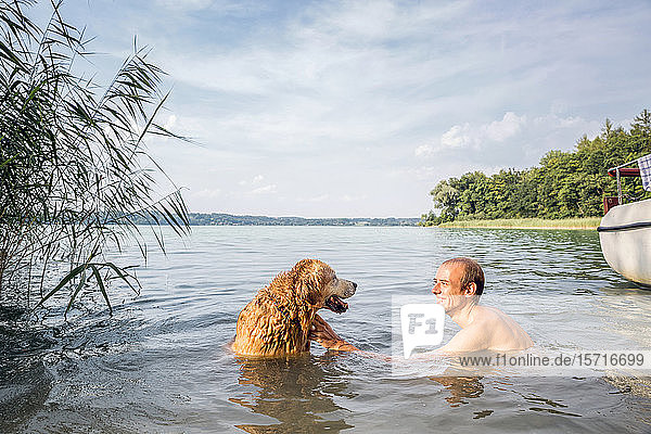 Young man with his Golden Retriever in a lake