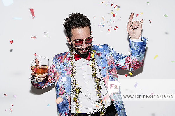 Cooler und stilvoller Mann mit farbenfrohem Anzug und Sonnenbrille tanzt auf einer Party