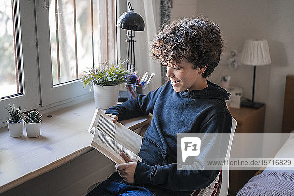 Lächelnder Junge liest zu Hause Buch