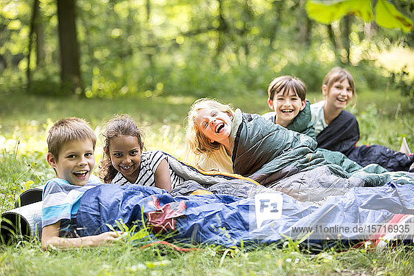 Schulkinder  die im Wald zelten und in Schlafsäcken liegen