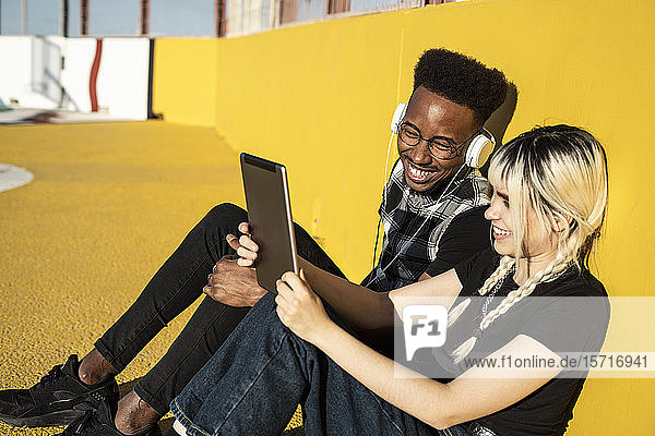Junges Paar vergnügt sich mit Kopfhörern und digitalem Tablet im Freien