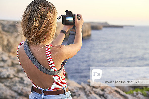 Junge Frau beim Fotografieren des Meeres