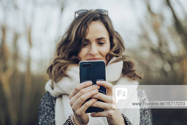 Portrait of young brunette woman holding smartphone