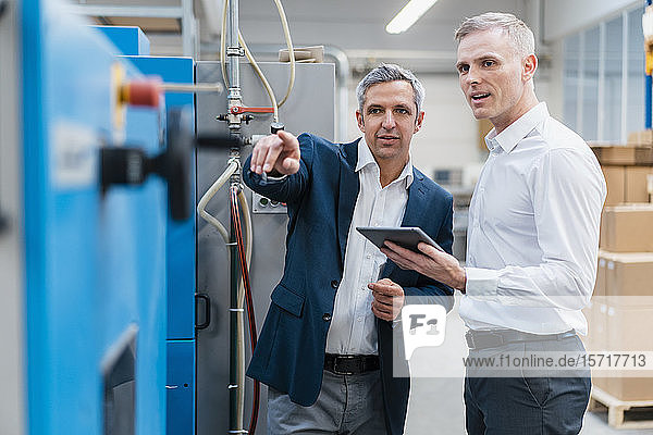 Two businessmen with tablet talking in a factory