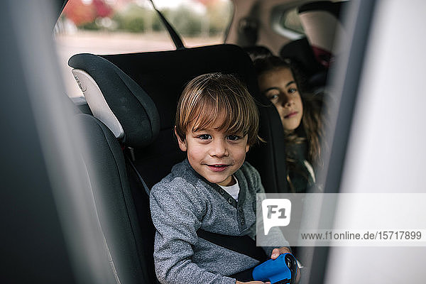 Portrait of smiling little boy sitting in child's seat in car