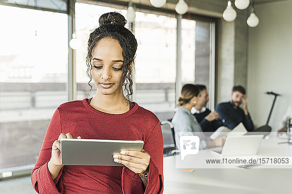 Junge Geschäftsfrau benutzt Tablette während einer Besprechung im Büro
