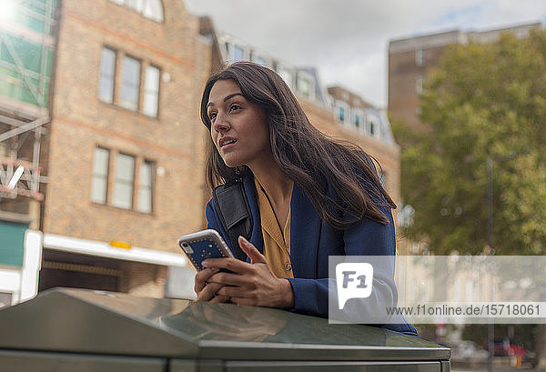 Porträt einer Frau  die ein Smartphone in der Stadt benutzt
