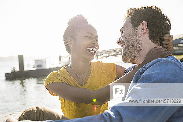 Happy young couple sitting at the waterfront  Lisbon  Portugal