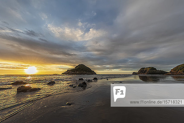 New Zealand  Tongaporutu  Cloudy sky over sandy coastal beach at sunset with Motuotamatea island in background