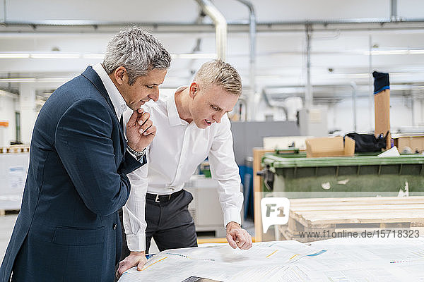 Two businessmen discussing paper in a factory