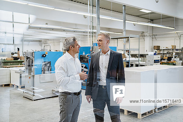 Two businessmen talking in a factory