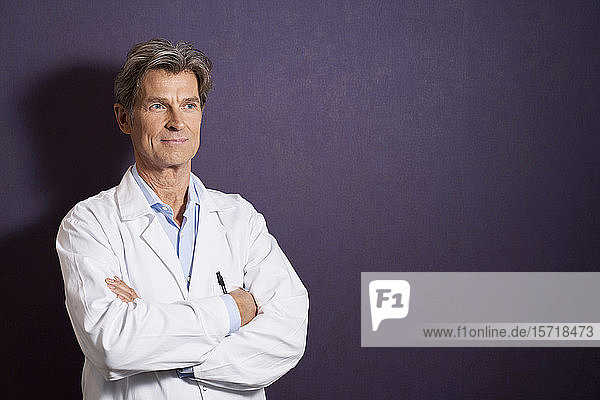 Porträt eines selbstbewussten Arztes vor einer violetten Wand