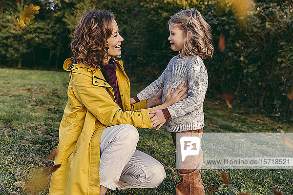 Lächelnde Mutter mit Tochter im Herbst auf einer Wiese