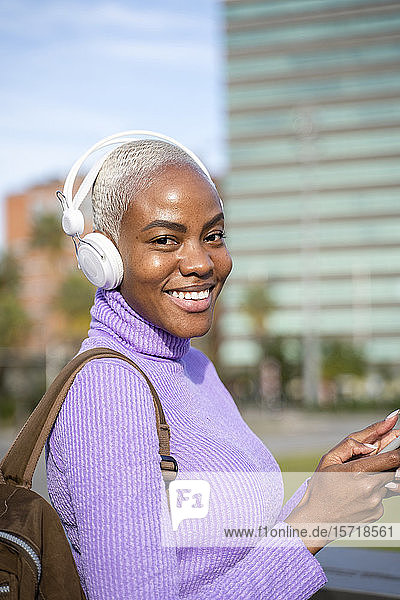 Porträt einer weißhaarigen Frau mit weißen Kopfhörern  die in der Stadt Musik hört