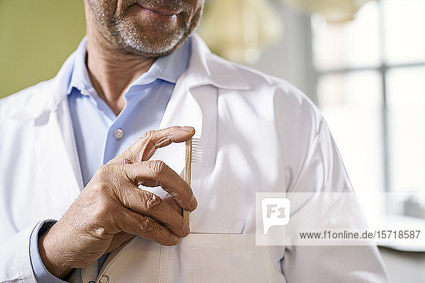 Close-up of dentist putting toothbrush in his pocket