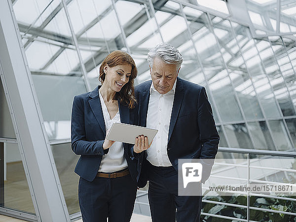 Lächelnder Geschäftsmann und Geschäftsfrau mit Tablett in modernem Bürogebäude