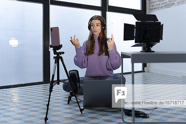 Portrait einer jungen Frau  die mit Laptop und Smartphone in einem Studio Aufnahmen macht