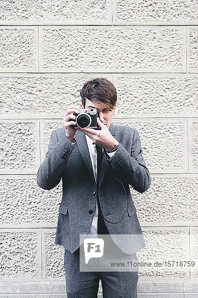 Portrait of young businessman taking photo with camera