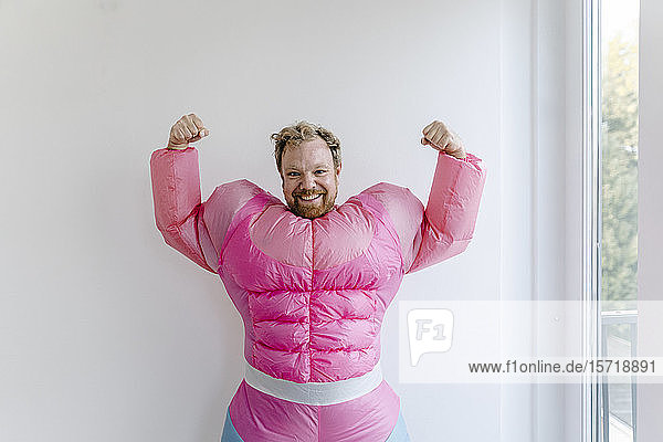 Stolzer Mann in rosa Bodybuilder-Kostüm  der seine Muskeln spielen lässt