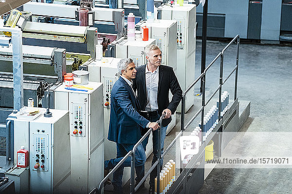 Two businessmen in a printing shop looking around