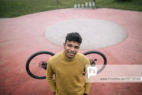 Porträt eines lächelnden jungen Mannes mit Fahrrad im Freien