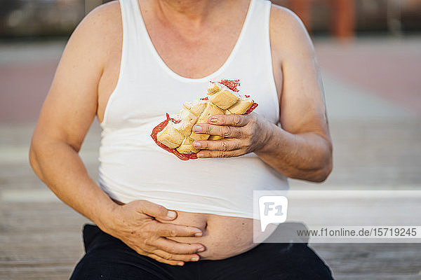 Man with beer belly holding sandwich