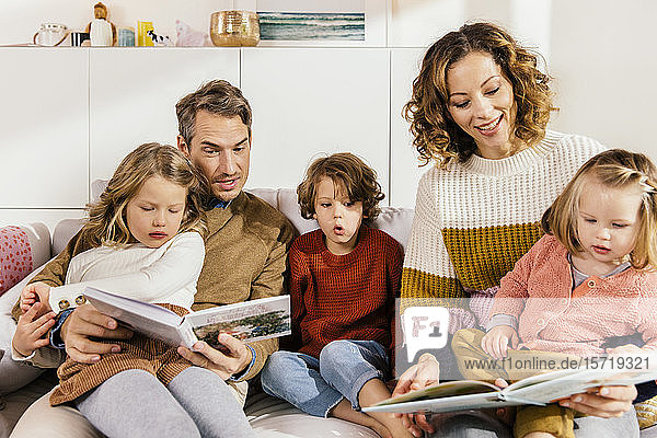 Family reading book with daughters on couch