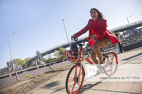Young woman riding through the city on a rental bike
