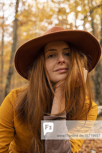 Porträt einer modischen rothaarigen jungen Frau im herbstlichen Wald