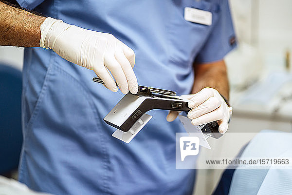 Nahaufnahme eines Zahnarztes mit speziellem Fotoapparat und Smartphone
