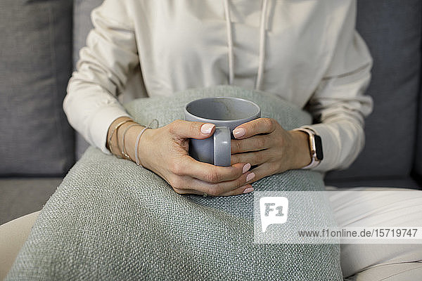 Scherenschnittansicht einer Frau  die sich bei einer Tasse Tee auf der Couch zu Hause entspannt