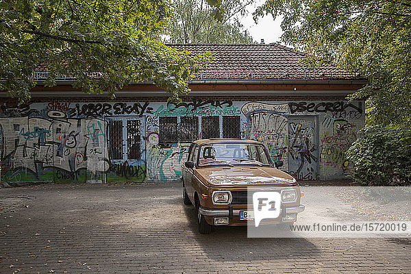 Deutschland  Berlin  Brauner Oldtimer vor einem mit Graffiti beschmierten Gebäude geparkt