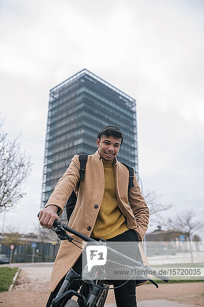 Porträt eines lächelnden jungen Mannes mit Fahrrad in der Stadt