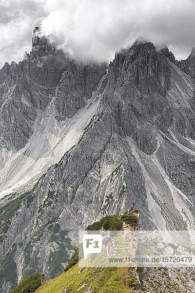 Bergsteiger  Frau auf einem Grat stehend und in ein Kar blickend  dramatische Wolken  in den hinteren Felswänden des Cimon di Croda Liscia  Auronzo di Cadore  Belluno  Italien  Europa
