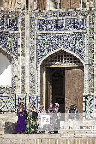 Frauen in traditioneller Kleidung vor dem Eingangsportal der Mir-Arab-Madrasa  Altstadt  Bukhara  Provinz Bukhara  Usbekistan  Asien