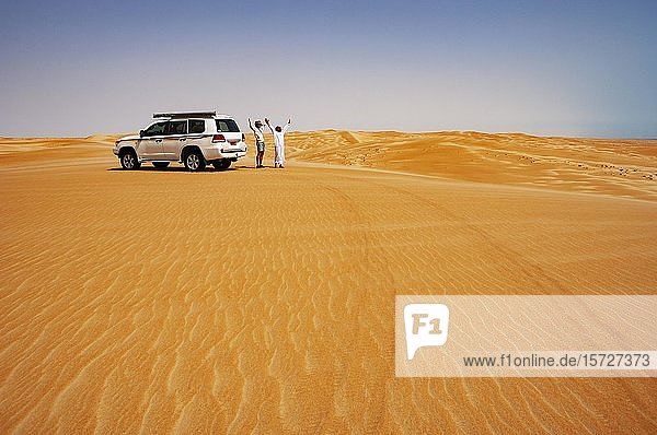 Tourist and Bedouin standing next to off-road vehicle  desert safari  desert Rimal Wahiba Sands  Oman  Asia
