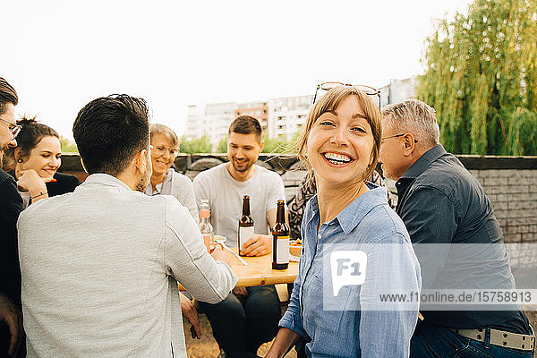 Portrait of smiling female sitting with friends and enjoying at social gathering